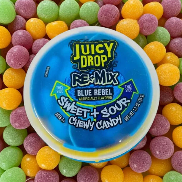 A round tub of Juicy Drop Re-Mix Blue Rebel Sweet + Sour Chewy Candy sits on top of a bed of colorful sour candies in green, pink, orange, and yellow.