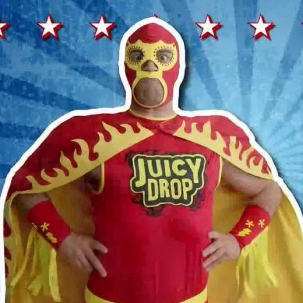 A person wearing a red and yellow lucha-style mask and costume with flame-patterned cape and armbands, standing against a blue starburst background. The chest area shows the words 'Juicy Drop'.