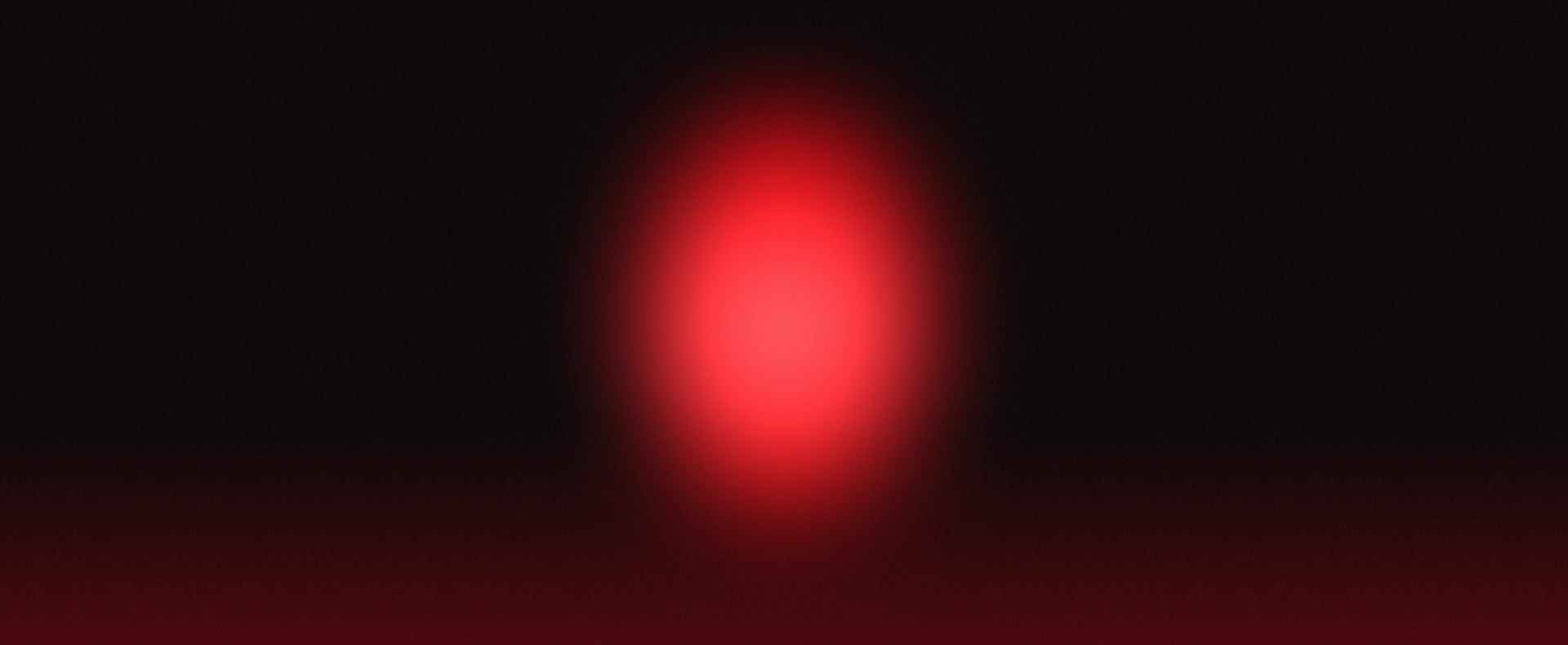 A soft, blurred red oval light or glow centered on a black background.